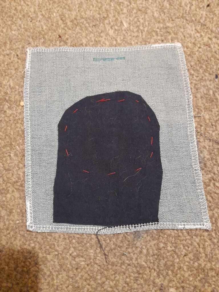 The back of the same sample. The dark fabric is tacked round the edges, behind the hole