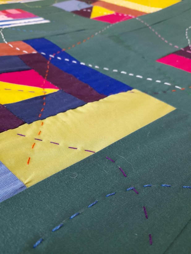 A close up of the quilt, with the brightly coloured stitches meandering across it.