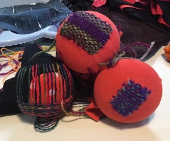 Close up of a pile of darning mushrooms, all with darning on them in different stages of completion.